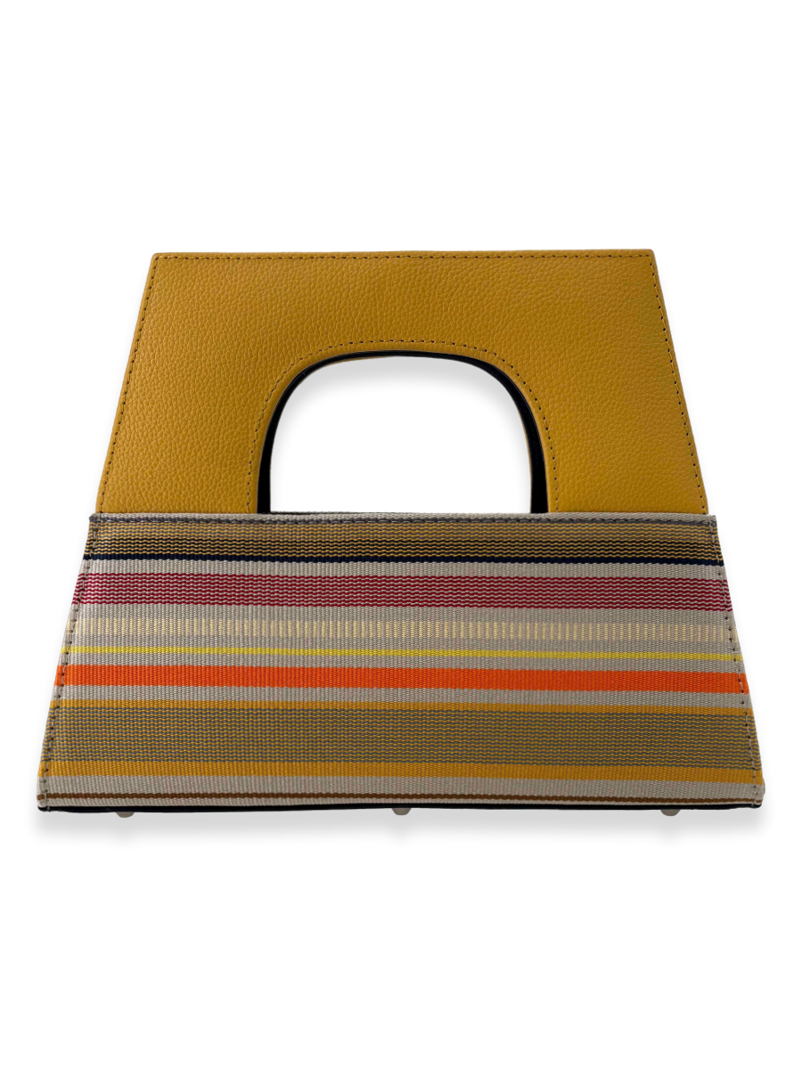 Contemporary luxury A-handle designer handbag crafted from mercerized Peruvian Pima cotton with multicolor woven stripes in yellow, ivory, orange, red, and charcoal tones. Features a structured yellow pebbled leather handle, navy patent leather interior grip, zip-top closure, and elegant architectural silhouette.