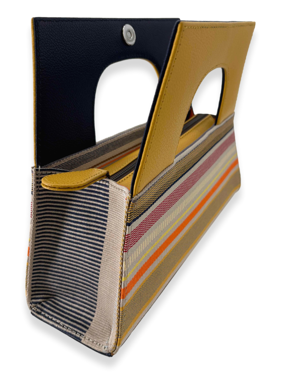 Designer A-handle handbag in mercerized Peruvian Pima cotton featuring yellow pebbled leather, multicolor striped textile, zip closure, and contemporary luxury styling made in Peru.