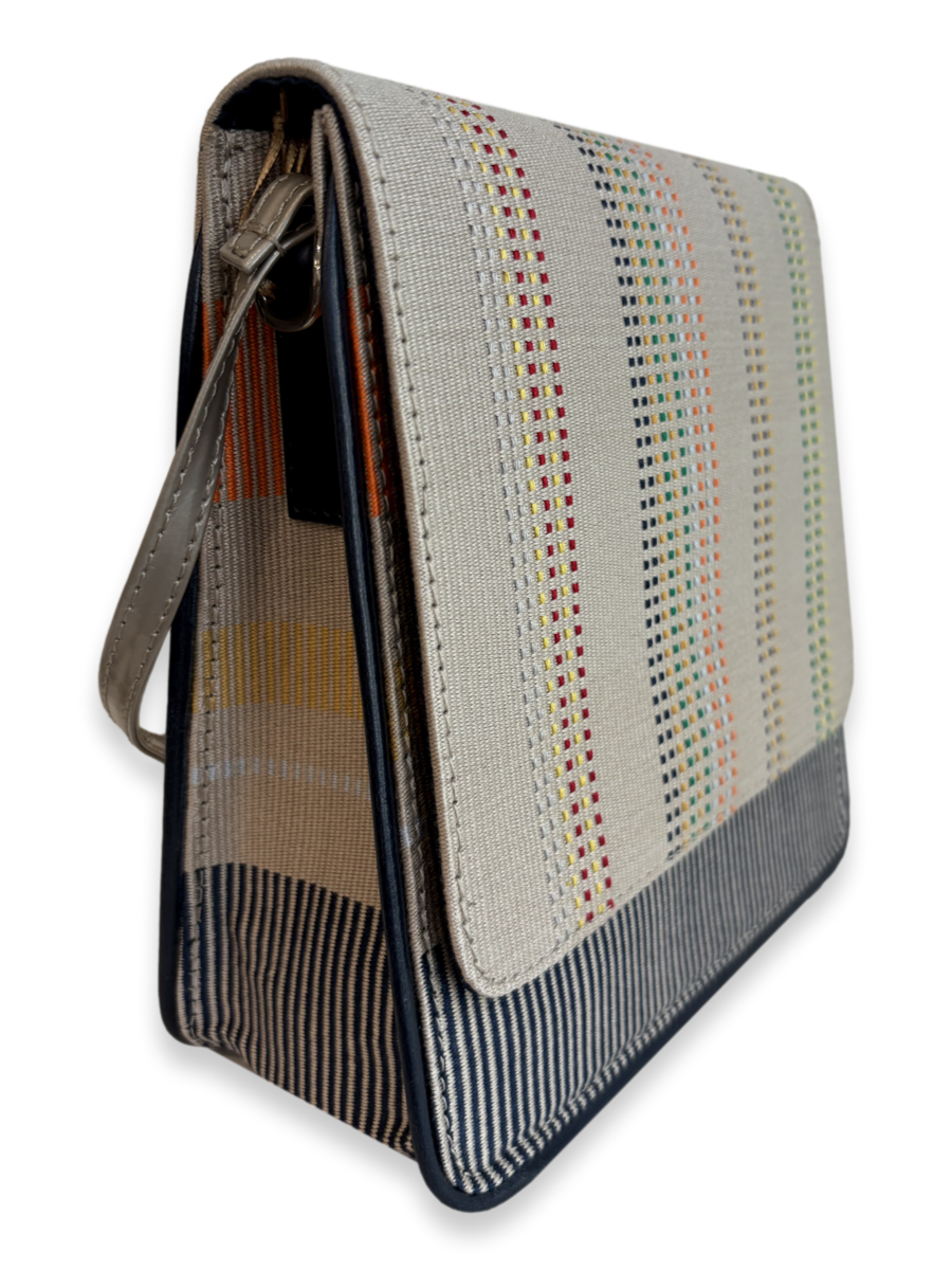 Angled side view of the Cocktail Crossbody Handbag showing its structured silhouette, woven Pima cotton textile, taupe leather strap and navy leather trim, made in Peru.