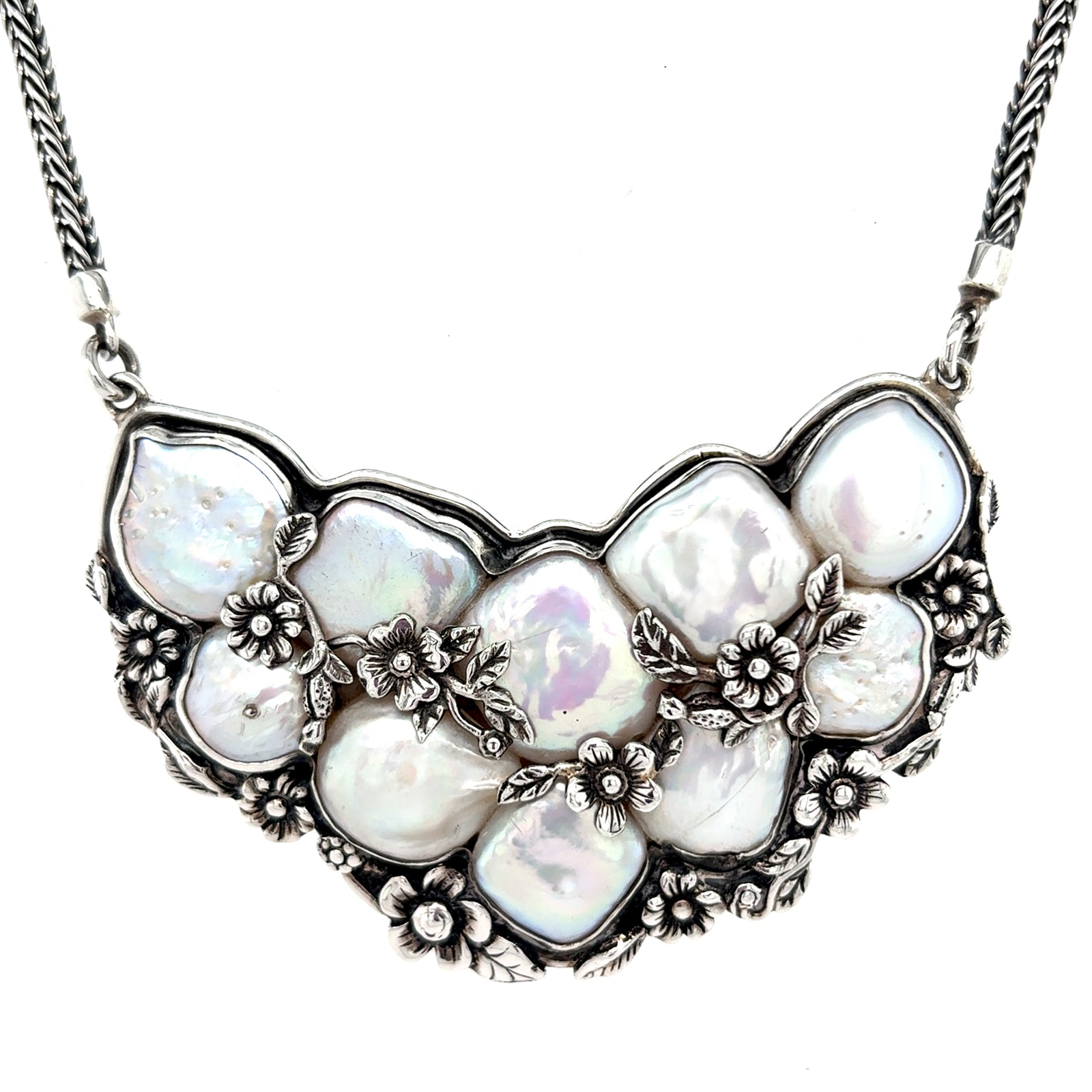 Freshwater baroque pearl bib necklace in 950 sterling silver with solid back, featuring iridescent organic pearls accented by intricate floral detailing in an elegant, sculptural design From Qinti The Peruvian Shop.