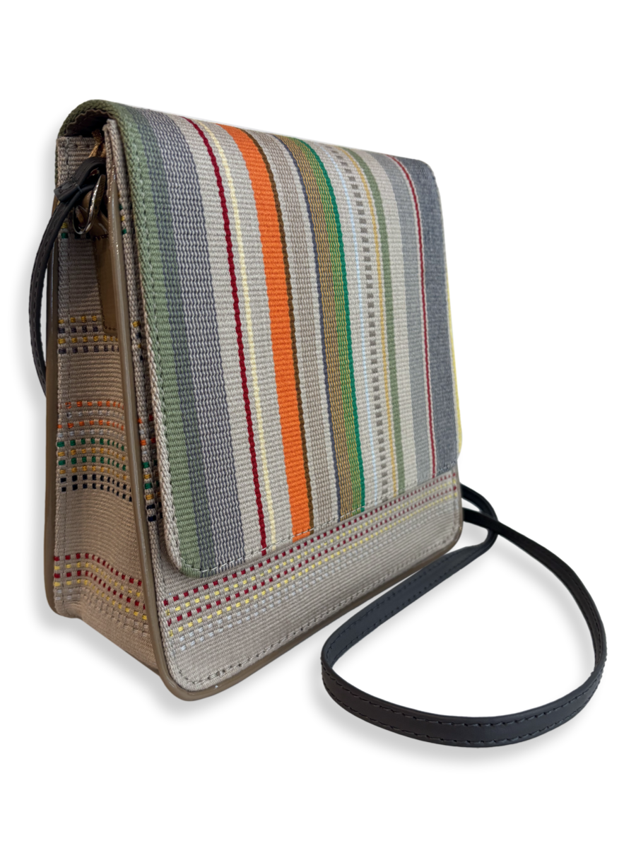 Angled view of the Cocktail Crossbody Handbag in woven mercerized Peruvian Pima cotton with multicolor stripes, smooth grey leather strap and taupe patent leather trim.