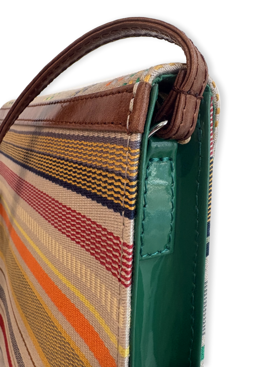 Close-up of the Curva designer crossbody handbag featuring premium mercerized Peruvian Pima cotton, smooth tan leather strap, glossy green leather side panel, and handcrafted luxury detailing.