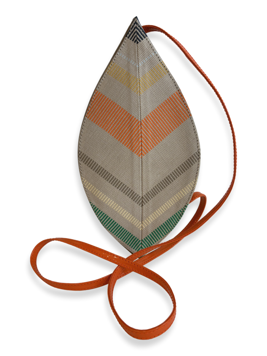 A teardrop-shaped shoulder bag with a chevron pattern in beige, orange, green, and gray, featuring a long rust-orange strap.