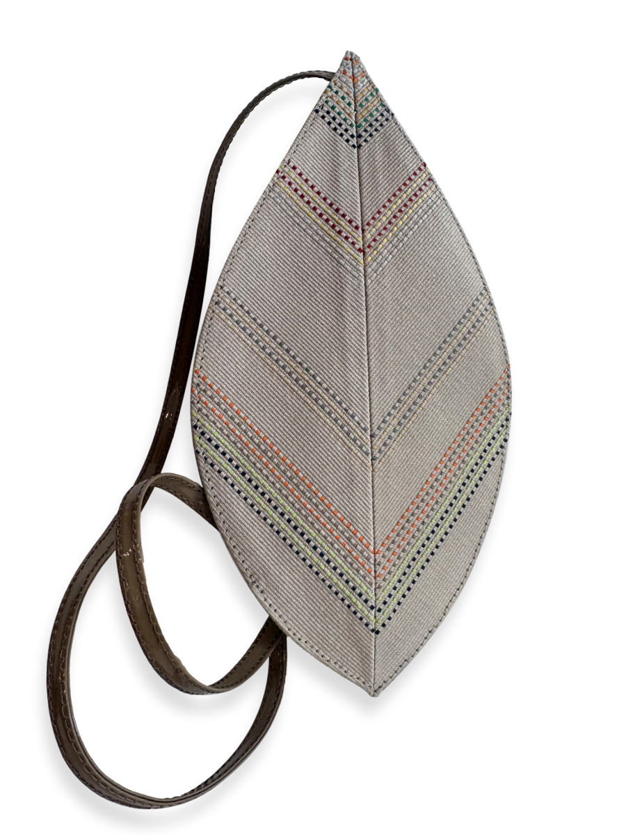 A leaf-shaped shoulder bag with a textured gray fabric body featuring geometric multicolor embroidered patterns, and a dark brown leather strap. Qinti the Peruvian Shop.