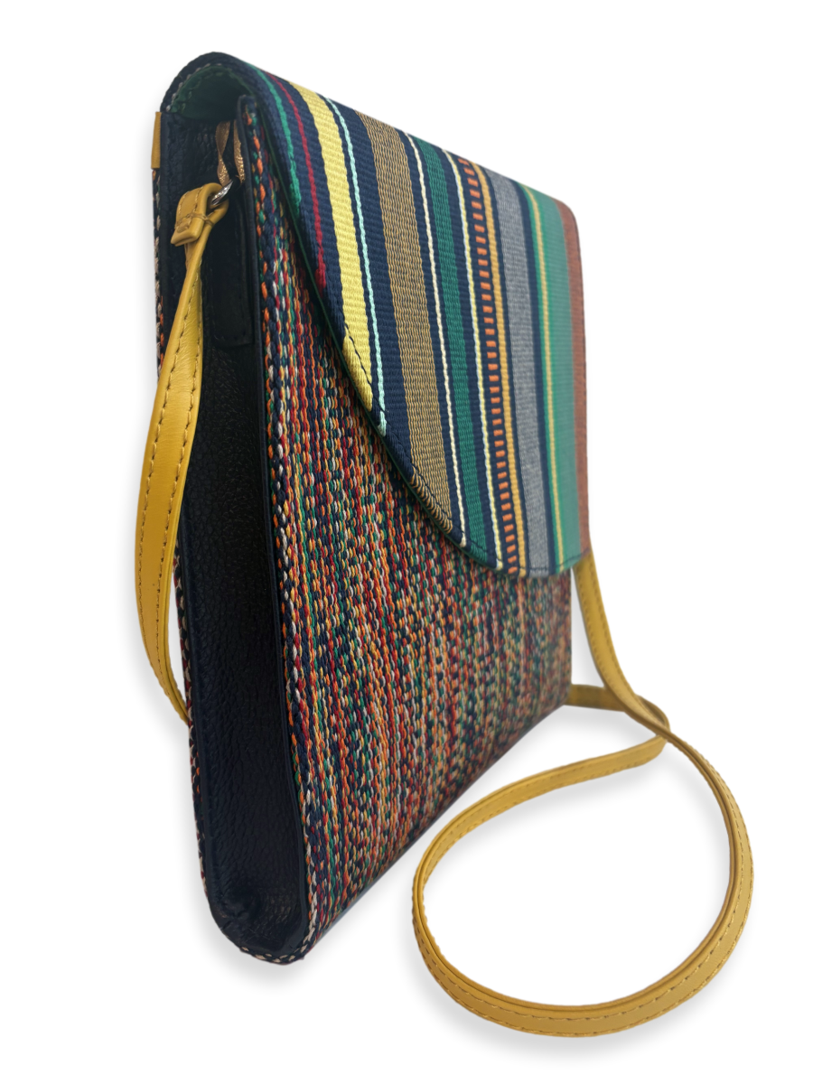 Angled view of the Curva Navy Multi designer crossbody handbag handcrafted in Peru with premium mercerized Peruvian Pima cotton, yellow pebbled leather strap, navy pebbled leather sides, and contemporary woven textile.